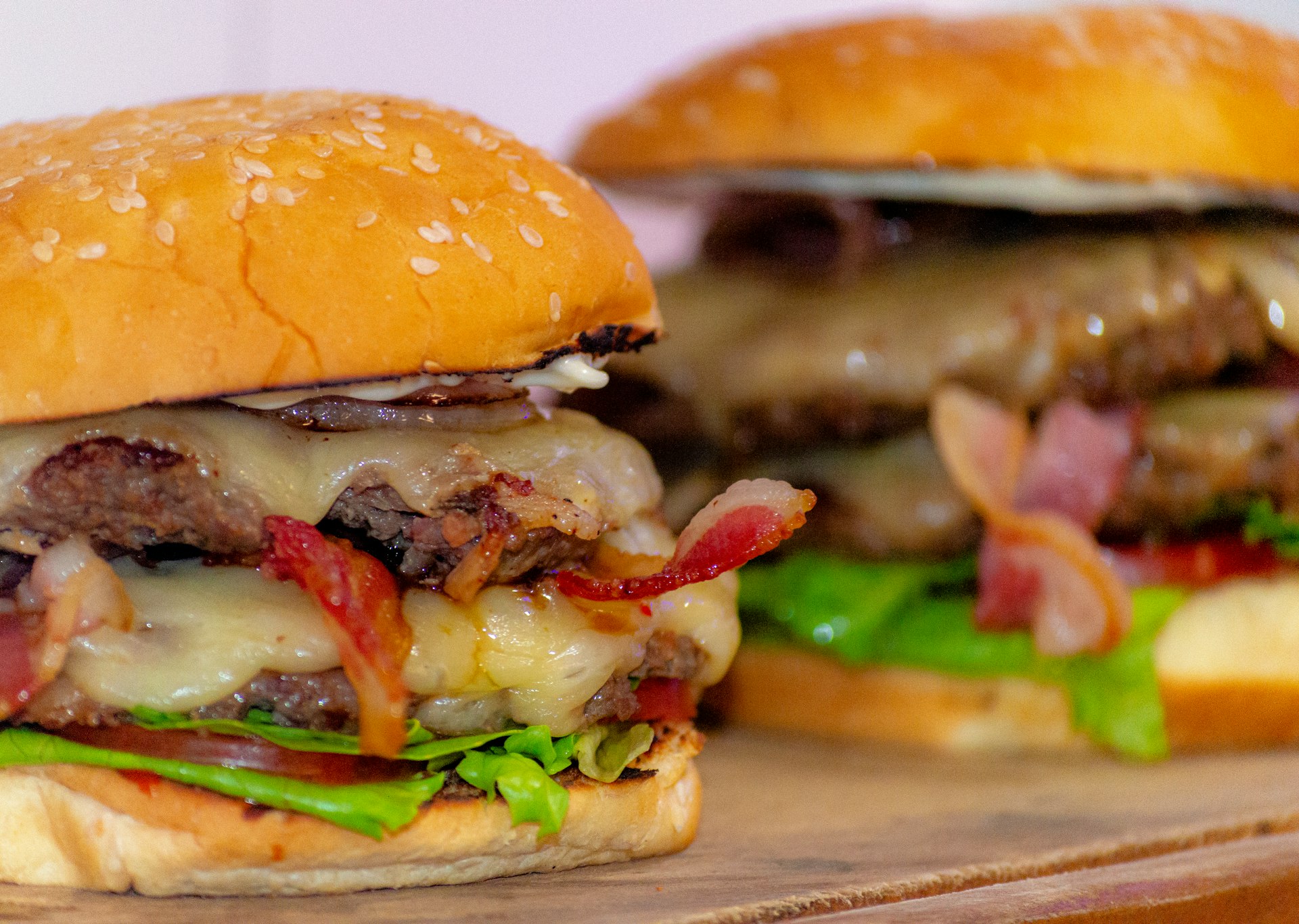 Two hamburgers sitting on top of a wooden cutting board